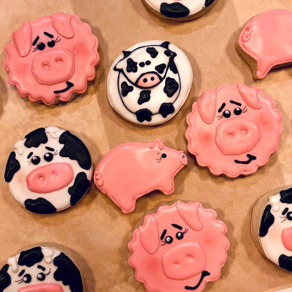 Decorative cookies shaped like pigs, cows, and pigs on a baking sheet.
